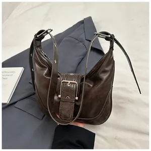 Detailed view of dark brown crescent bag featuring metallic buckle and textured leather