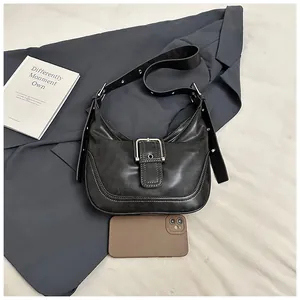Close-up of black retro saddle bag with silver metal buckle and contrast stitching details