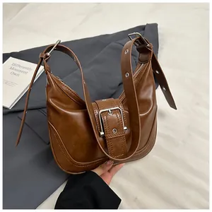 Detail of retro brown hobo bag featuring silver buckle strap and textured leather finish