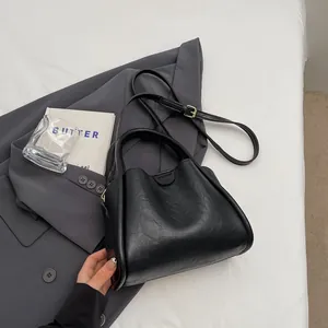 Black vintage leather shoulder bag with double handles and adjustable strap in a stylish setup