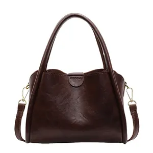 Vintage dark brown crossbody bag with top handle and golden hardware on white background