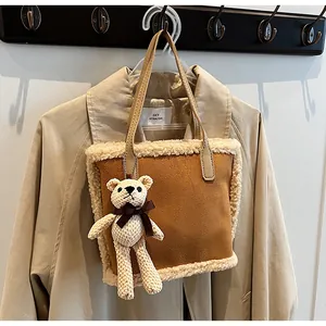 Close-up of brown suede tote bag with cream fleece trim and a cute bear keychain accessory