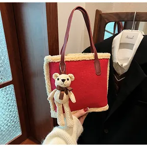 Detail of red tote bag with plush lamb wool trim and a cute knitted bear charm