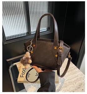 Detailansicht der braunen Bucket-Bag aus Kunstleder mit Ziernähten, Nieten und Anhänger