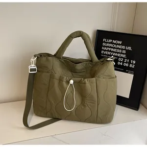 Dettaglio della borsa tote in nylon trapuntato verde scuro con cuciture a onda e tasca