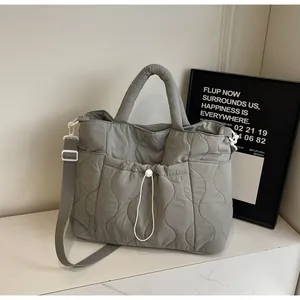 Dettaglio della borsa tote in nylon trapuntato grigio con cuciture e tasca con lacci