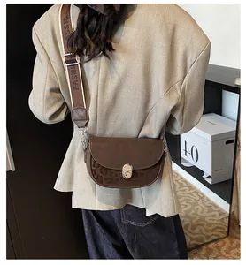 Detail of a brown suede saddle bag with leopard print and a wide fashion strap