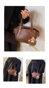 Makroaufnahme der braunen Beuteltasche mit Goldnieten und Plüschmonster-Anhänger