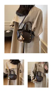 Detail der dunkelbraunen Eimertasche aus Leder mit Nieten und flauschigem Monster-Anhänger