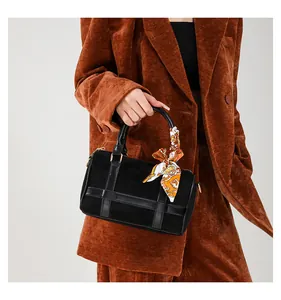 Detail of black suede Boston bag with patterned silk scarf wrapped on handle