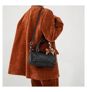 Detail view of a black Boston barrel bag with a decorative scarf and gold hardware