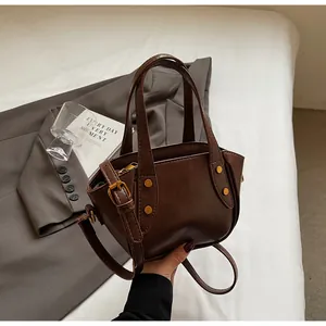 Detailaufnahme der braunen Beuteltasche mit Goldnieten und verstellbarem Schultergurt