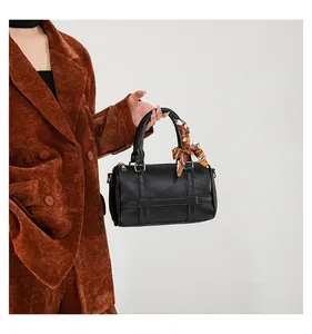 Detail of black Boston bag with lychee texture, golden hardware and printed silk scarf