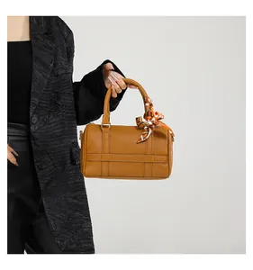 Detail of caramel Boston bag featuring cross-patterned leather and decorative silk scarf