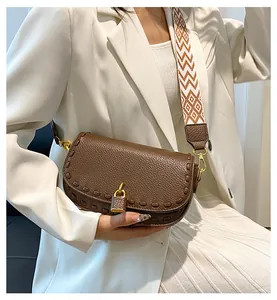 Détail du sac besace marron avec large bandoulière tissée et cadenas doré décoratif