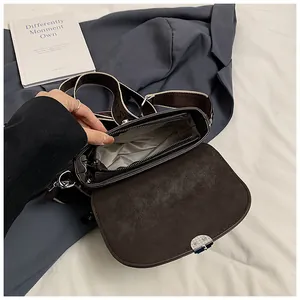 Interior view of brown faux suede saddle bag with compartments and wide woven strap