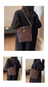 Detail view of leopard print bucket bag with metal rivets and adjustable strap