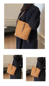 Detailed macro view of the brown suede texture and golden rivet accents on the bucket bag