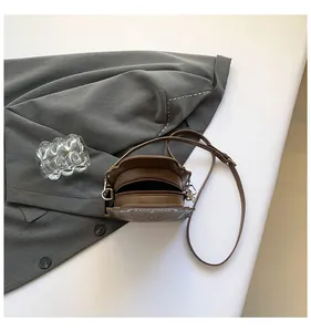 Dettaglio della borsa a tracolla marrone ondulata con stampa vintage e zip in metallo