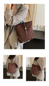 Detail of dark brown suede bucket bag featuring golden studs and buckle closure