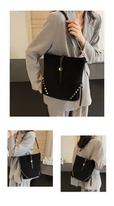 Detail view of black matte bucket bag with gold rivets and metallic buckle strap