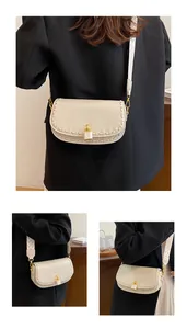 Détails du sac selle crème avec texture litchi, bords tressés et bandoulière large