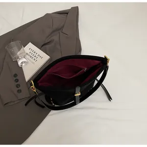 Detailed interior of black bucket bag with burgundy lining and gold metal rivets