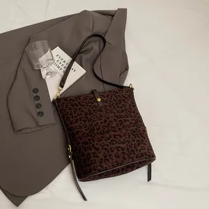 Brown leopard print suede bucket bag with gold hardware and a long crossbody strap