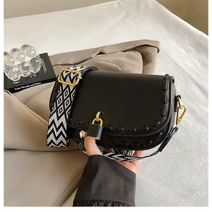 Détail du sac bandoulière en cuir noir avec bord tressé et fermoir cadenas doré chic