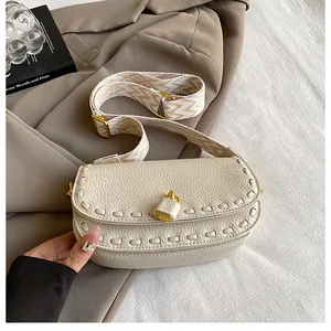 Détail du cuir grainé crème avec fermoir doré et bandoulière tissée à motifs