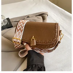 Détail du sac en cuir grainé marron avec une large bandoulière à motifs géométriques