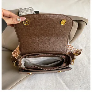 Détail du sac selle en cuir marron grainé avec large bandoulière géométrique