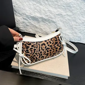 Leopard print baguette bag with white trim and bow details on vintage background
