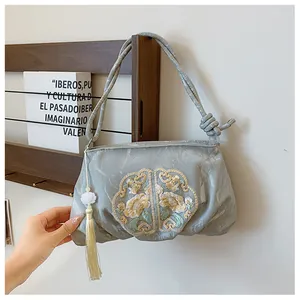 Detailansicht der chinesischen Stickerei und langen Quaste an einer grauen Stofftasche