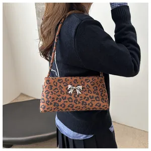 Close-up of leopard print underarm bag with silver metal bow and matching shoulder strap
