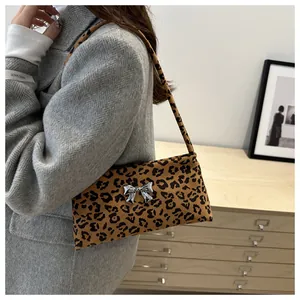 Detailed view of leopard print shoulder bag with silver bow accent on model