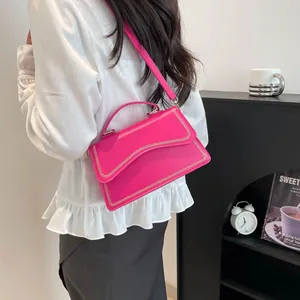 Sac à main chic en cuir magenta avec bordure chaîne dorée porté par un mannequin stylé