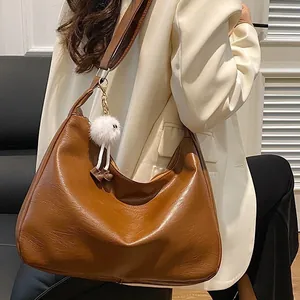 Grand sac cabas en cuir marron avec breloque monstre en peluche sur un modèle élégant