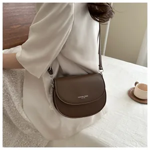 Détail du sac de selle en cuir marron foncé avec inscription Fashion Trend blanche