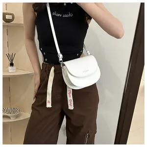 Détail du sac selle blanc en similicuir avec bandoulière et boucles métalliques