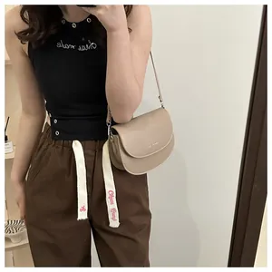 Selfie miroir montrant une sacoche selle demi-lune kaki avec ferrures métalliques