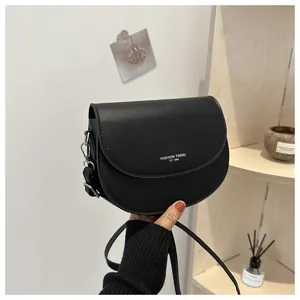 Détail d'un sac selle noir mat avec texte tendance blanc et crochets en métal argenté