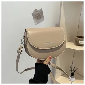 Détail du sac selle beige clair avec boucle en métal argenté et bandoulière réglable