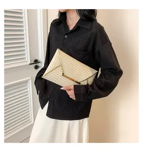 Dettaglio della pochette a busta color champagne con trama a nido d'ape e cornice a V