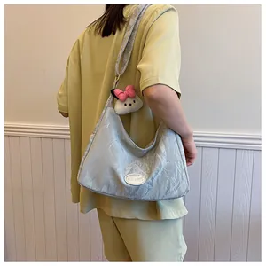 Detail of light blue pleated dumpling bag with white logo patch and plush charm
