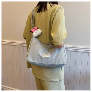 Close-up of silver pleated hobo bag with metallic texture and plush cartoon charm