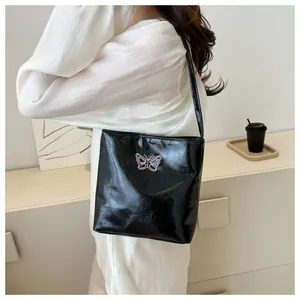 Detail of black glossy shoulder bag with pink butterfly embroidery for women