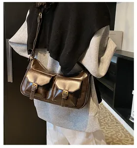 Dettaglio borsa a tracolla marrone vintage con tasche anteriori e fibbie dorate