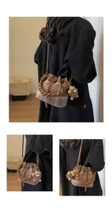 Détail du sac seau en laine à carreaux avec poignée tressée et charm peluche marron