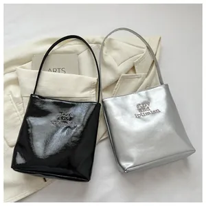 Detail of minimalist bucket bags with glossy wrinkled finish in black and silver colors